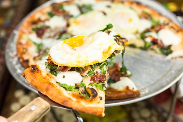 breakfast pizza with a sunny-side-up egg and vegetables