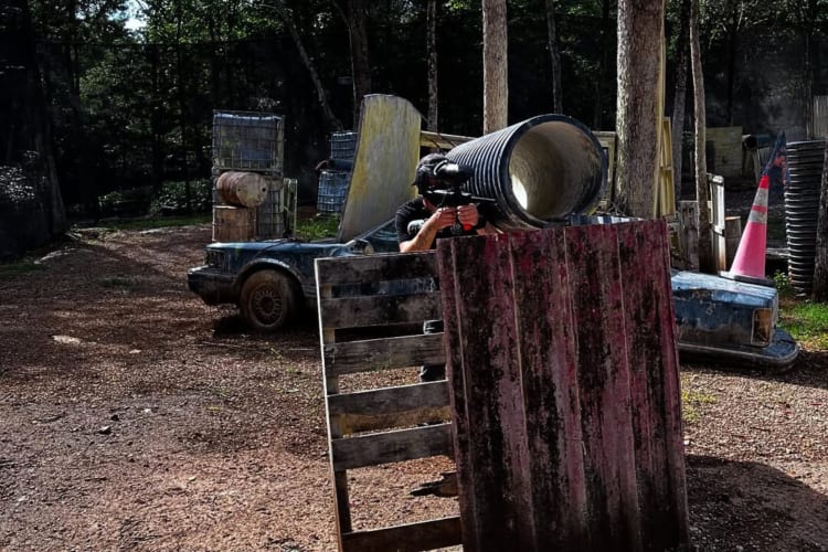 A person taking cover behind wooden panels during a paintball game