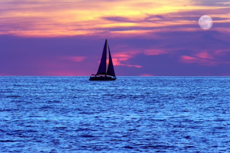 A boat sailing on the sea at sunset