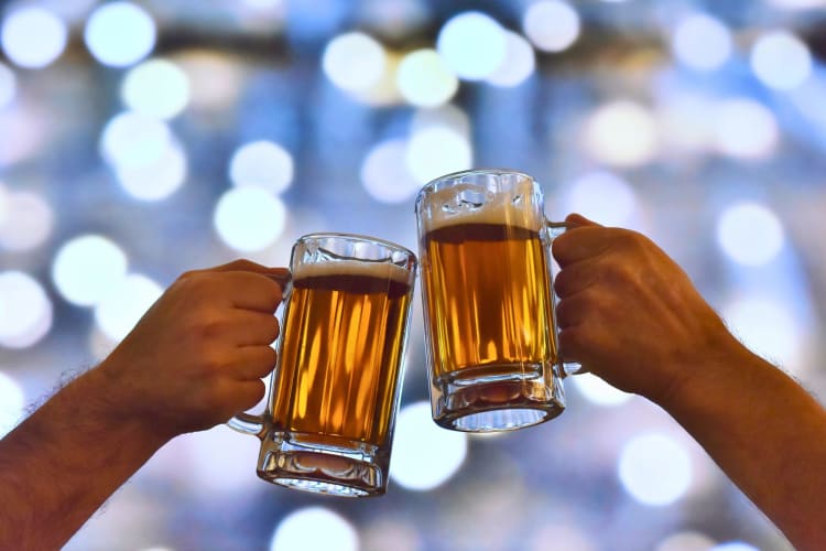 Two hands holding steins of beer.