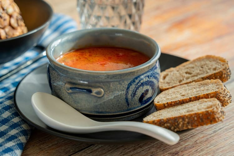 A bowl of tomato soup with bread slices.