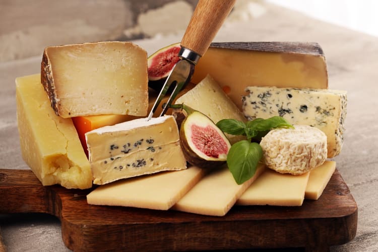 Various cheeses and two halves of a fig on a wooden board