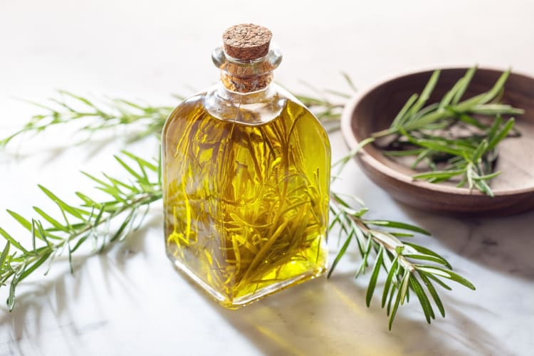 A glass bottle of oil filled with herbs