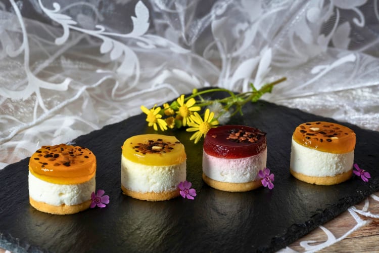 Colorful mini cheesecakes on a slate board.
