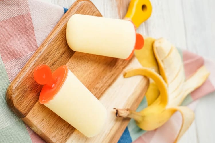 Two banana popsicles next to a banana.