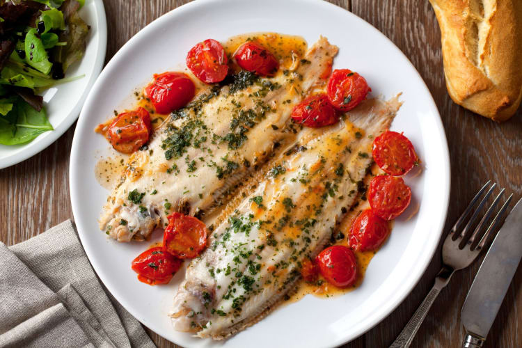 Cooked sole with cherry tomatoes on a plate.