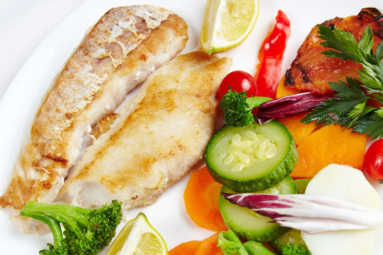 A hake filet with grilled veggies.