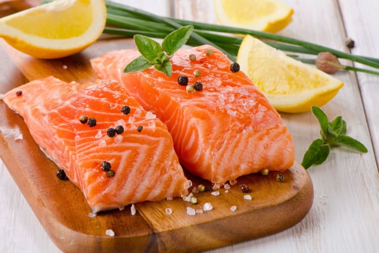 Raw salmon fillets on a wooden board.