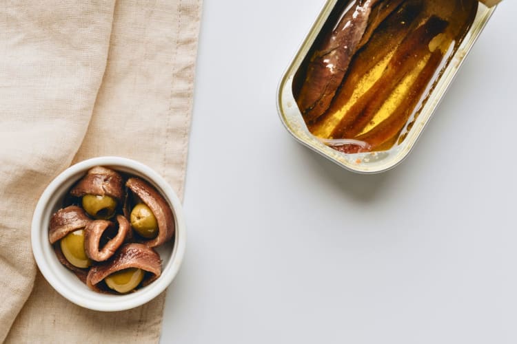 Close-up shot of a can of anchovies beside olives.