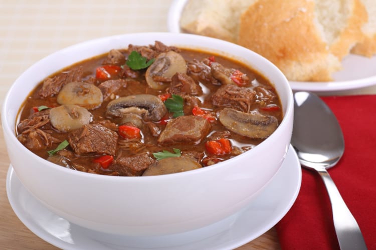 A bowl of beef bourguignon on a table.