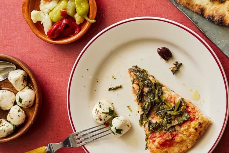 A pizza slice on a plate next to two balls of cheese