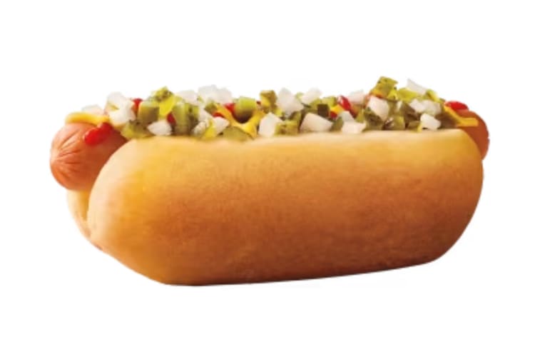 Hot dog loaded with relish, tomatoes, pickles and peppers on a soft hot dog bun.