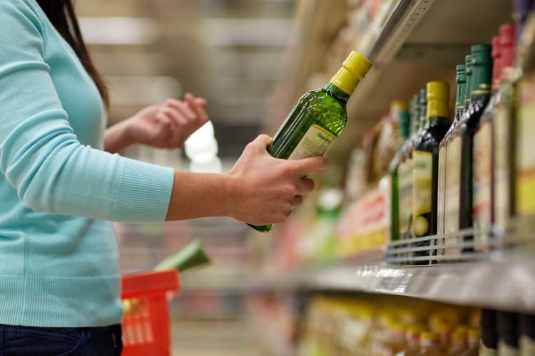 Woman buying olive oil in a grocery store.