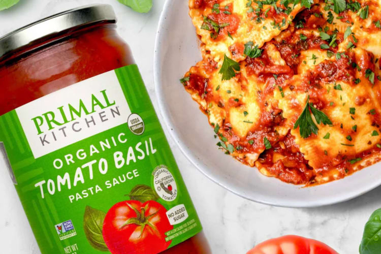 A jar of pasta sauce next to a bowl of pasta.