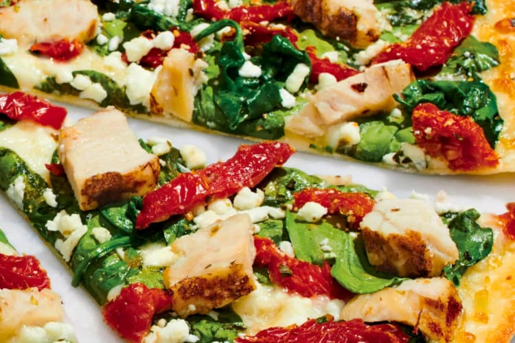 Pizza with Grilled Chicken, Spinach, Sun-Dried Tomatoes, Zesty Herbs, Chopped Garlic, Crumbled Feta, Whole-Milk Mozzarella, and Olive Oil Blend & Garlic Sauce.