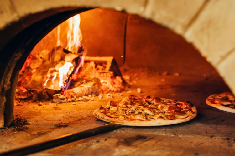 Italian pizza is cooked in a wood-fired oven.