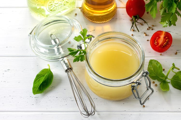 Salad dressing in a jar next to a whisk
