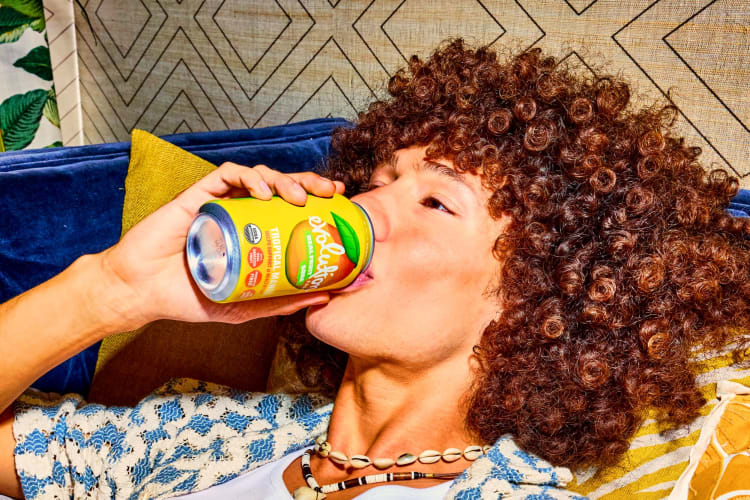 A woman lying back drinking a soda.