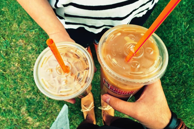 Two people holding cups of iced coffee.