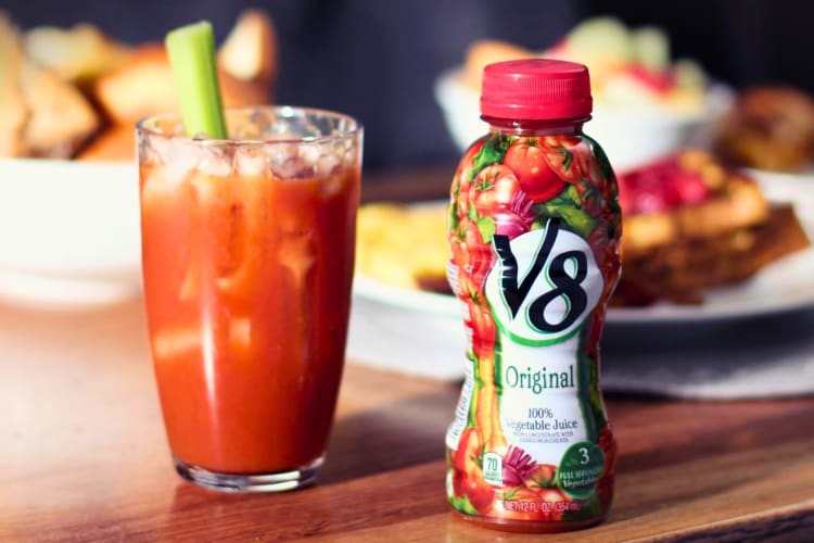 A glass of V8 vegetable juice next to the bottle.