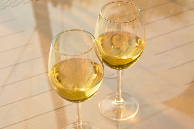 Two glasses of white wine on a table.
