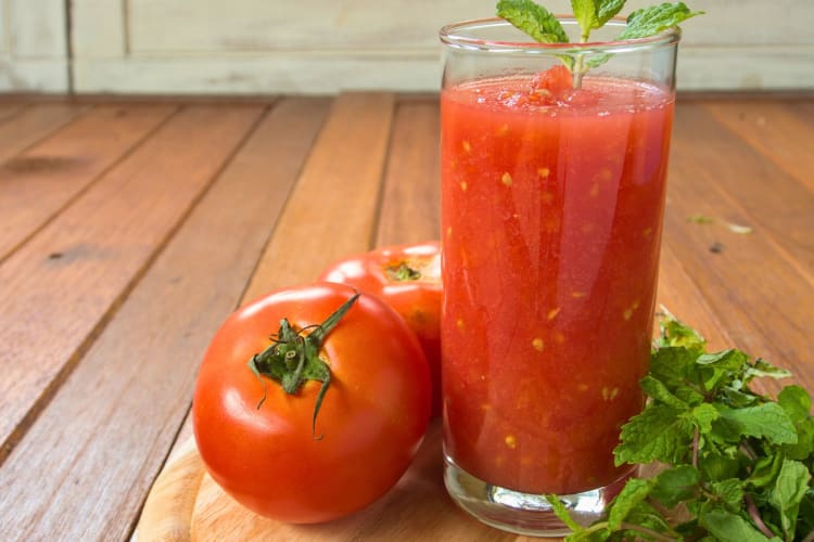 A glass of tomato juice with a tomato.