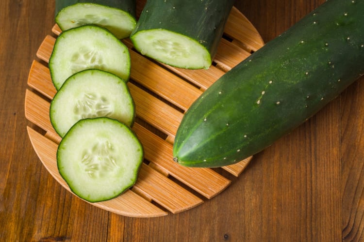 Sliced cucumber on a wooden chopping board.