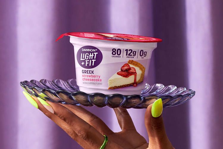 A cup of Dannon Light + Fit high-protein yogurt on a glass tray