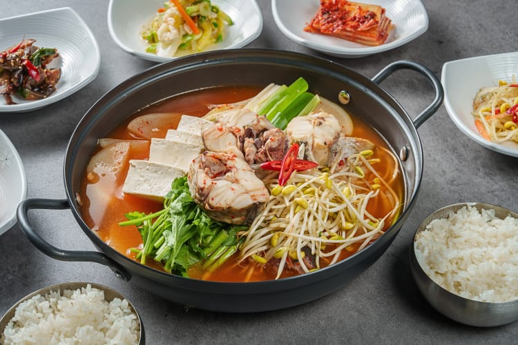 A hot pot surrounded by smaller plates of different foods