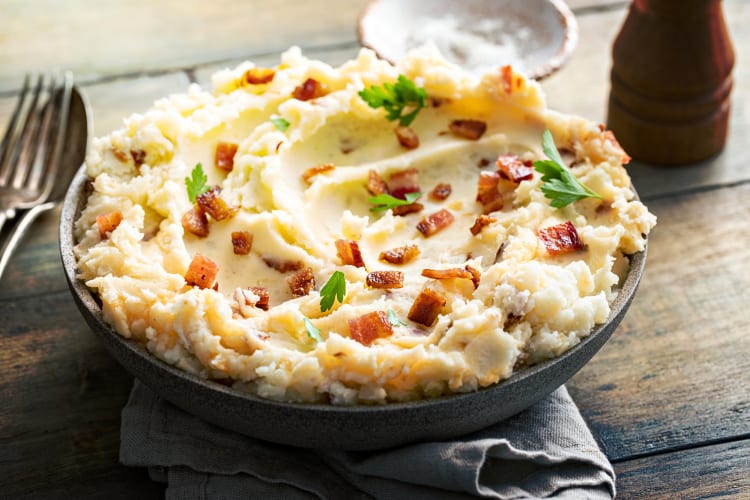 A bowl of mashed potatoes topped with bits of bacon