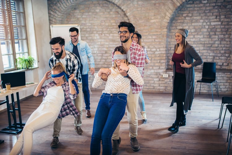 A team playing a game in their office where blindfolded people are caught by others