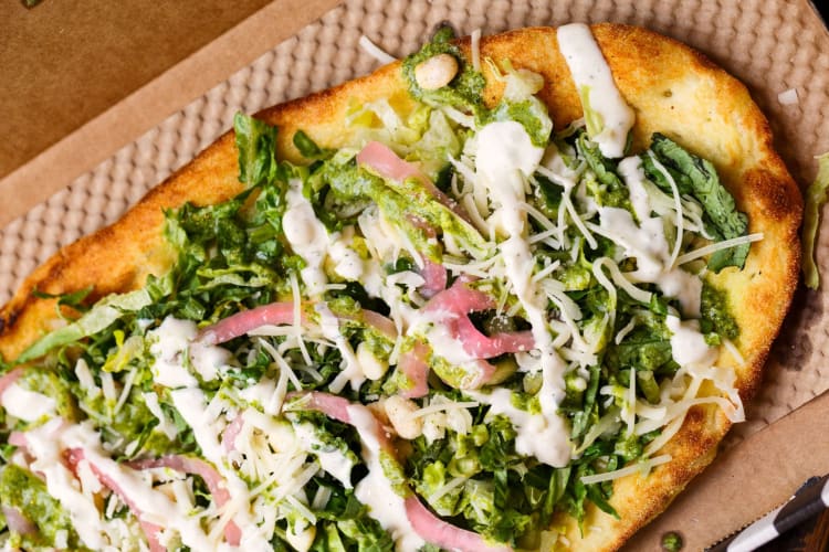 Overhead view of pesto pizza with red onion topping.