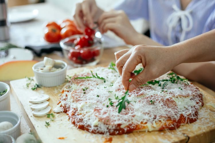 Two people making homemade pizza in kitchen.