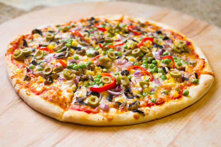 A vegetarian pizza on a wooden table. Is pizza bad for you?