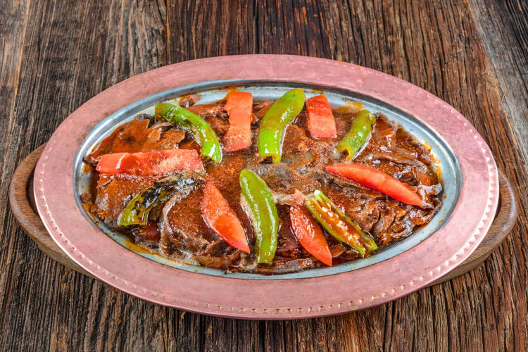 İskender kebap — a Turkish food — on a plate situated on a wooden surface