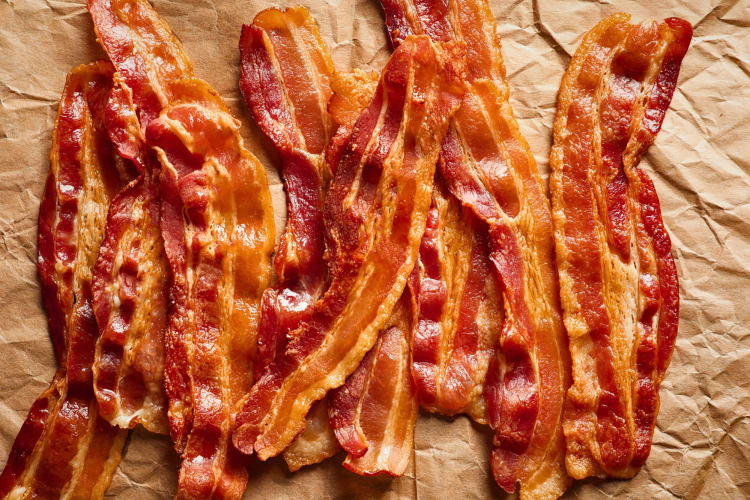 Cooked bacon rashers on parchment paper.