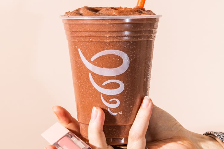 A hand holding a chocolate smoothie from Jamba Juice