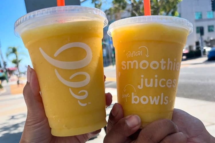 Two hands holding pineapple-flavored Jamba Juice smoothies