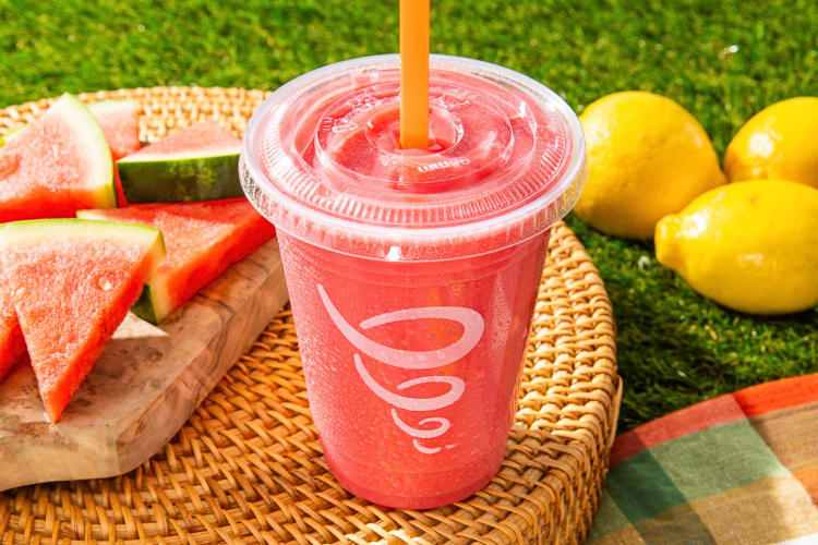 A watermelon-flavored smoothie in front of watermelon slices and lemons