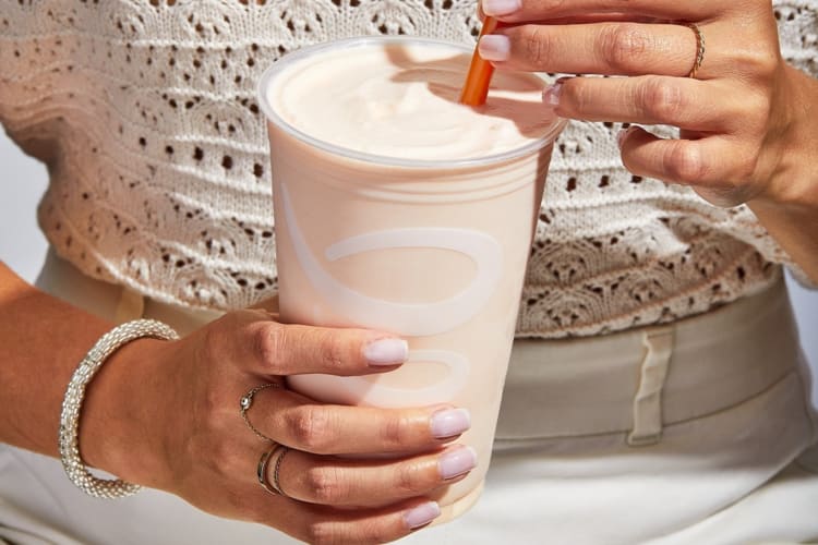 Woman holding a light pink Jamba Juice smoothie