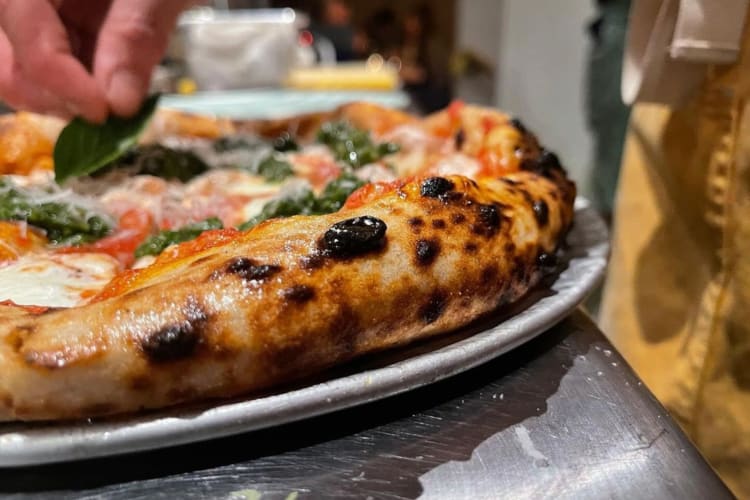 tomato and mozzarella pizza smothered with a green basil herb mix and pecorino