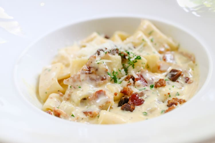 Chicken carbonara pasta with fried bacon and grated cheese