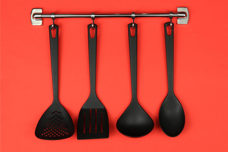 Black kitchen utensils on silver hooks