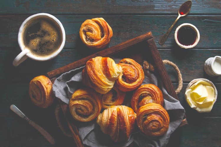 A basket of fresh pastries and fresh black coffee.