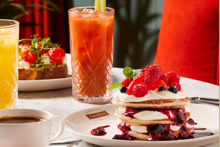 Stack of berry pancakes with a bloody mary cocktail and cup of coffee.