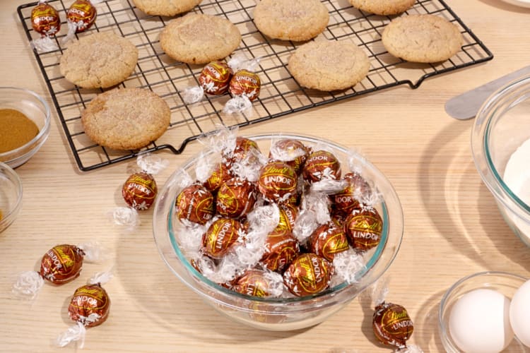 Snickerdoodle Lindor chocolate flavor truffles in front of a grid topped with snickerdoodles