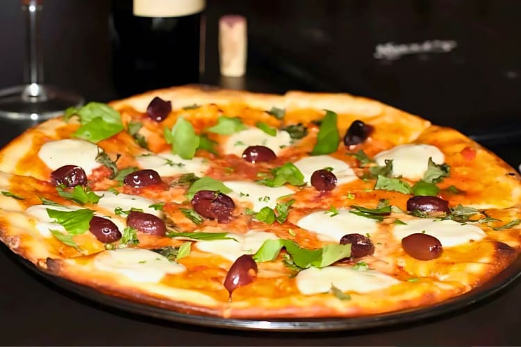 Pizza topped with Kalamata olives and fresh basil