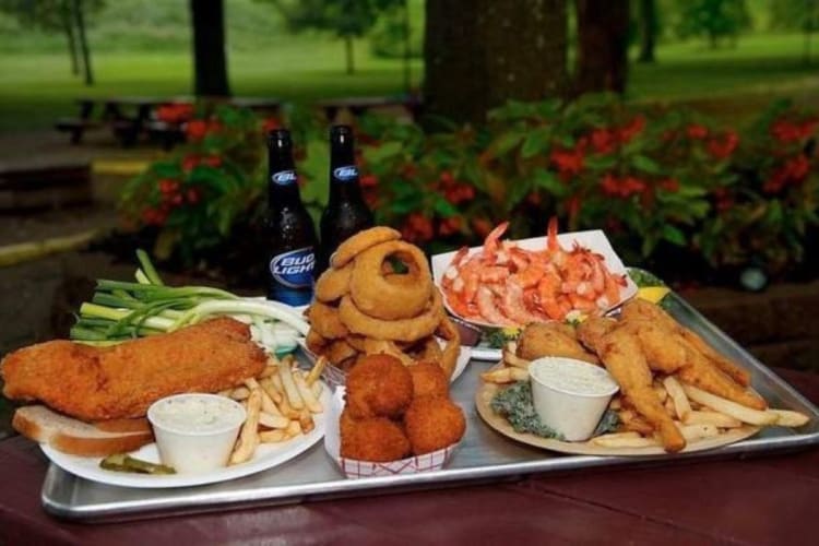 A selection of fried fish sandwiches, beers, shrimps, fries on a table.