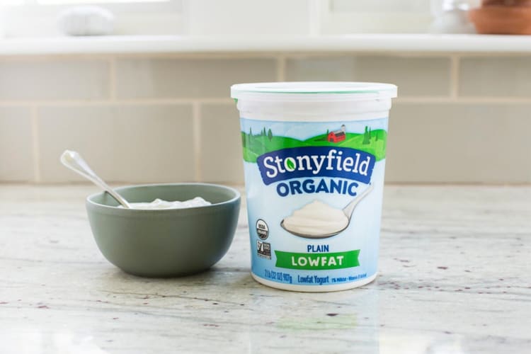 A tub of Stonyfield Organic Lowfat Yogurt next to a bowl of yogurt