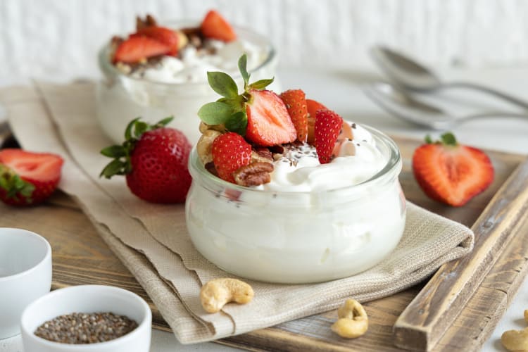 Greek yogurt in a clear jar topped with strawberries, chia seeds and nuts